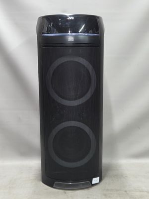 une enceinte noire posée sur une table, à côté d'un fond blanc