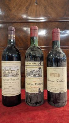 three bottles of wine are lined up on a red cloth