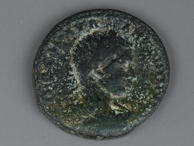 une vieille pièce de monnaie sur laquelle est représenté un visage, posée sur une table