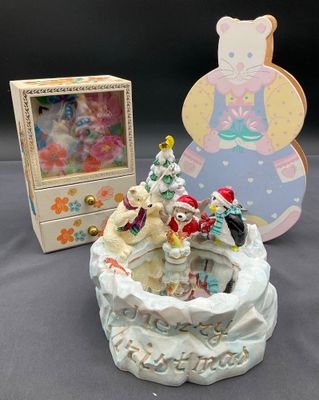 une figurine assise à côté d'une boîte contenant un ours en peluche