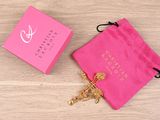 the pink bag is next to a gold cross on a wooden table