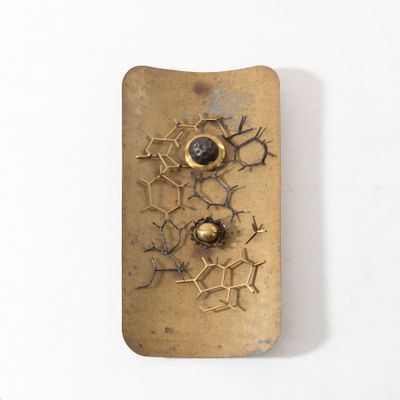 un vieil objet métallique percé d'un trou, posé sur une surface blanche