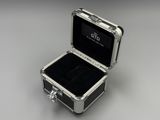 an open silver case with a black interior on a gray surface