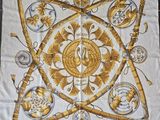 une photo d'un foulard carré orné de motifs dorés et blancs