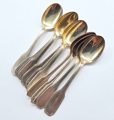 six cuillères et un repose-cuillère sur une surface blanche