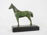 statue en bronze représentant un cheval, posée sur un socle noir, sur fond blanc