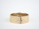 a close up of a gold bracelet on a white surface
