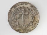 a silver coin with a cross on it on a white surface