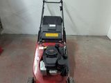 a red lawn mower sitting on the floor in a garage