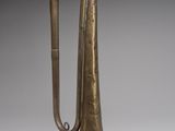 an old brass trumpet with a long handle on a gray background