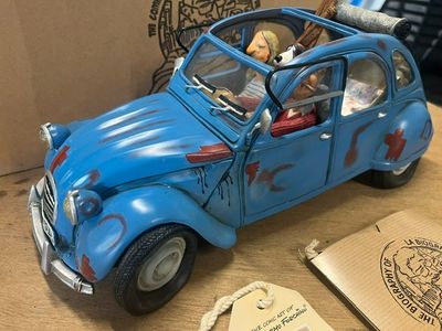 une petite voiture bleue avec un chien sur la banquette arrière