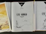 three books are lined up on a table with a black background