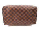 the brown and black checkered purse is sitting on a white surface