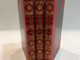 three red books sitting on top of each other on a white surface