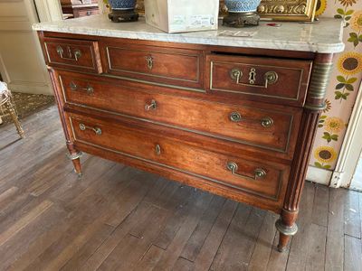 une commode au plateau en marbre dans une pièce décorée de tournesols