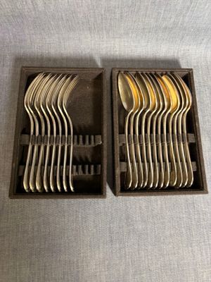 deux boîtes contenant des fourchettes et des cuillères, posées sur une table