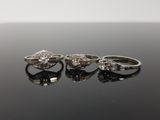 three diamond rings on a black surface with a white background