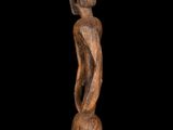 a wooden sculpture of a woman standing on a black background