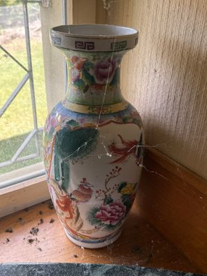 un vase posé sur le rebord d'une fenêtre, devant celle-ci