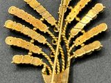 a gold brooch that has a bunch of gold beads on it