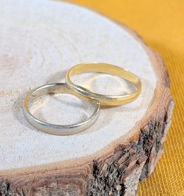 two wedding rings sitting on top of a piece of wood