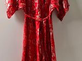 red dress hanging on a hanger next to a white wall
