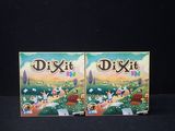 two boxes of dixit on a black surface with a black background