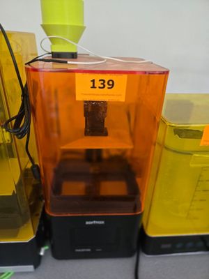 une imprimante 3D jaune et orange posée sur une table à côté d'autres imprimantes 3D jaunes et noires