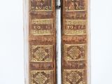 two old books sitting on top of each other on a white surface