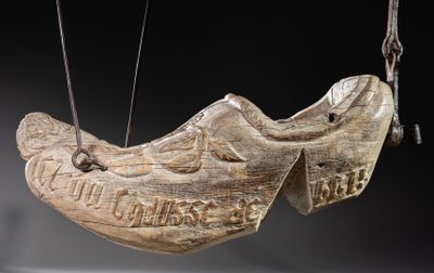 a wooden shoe hanging from a string on a black background