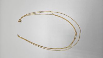 a close up of a gold necklace on a white surface