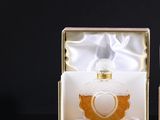 packaging for a perfume bottle in a gold and white box on a black background