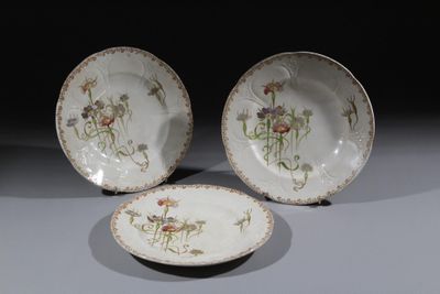 trois assiettes ornées de fleurs sont posées sur une table