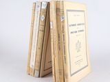 several old books stacked on top of each other on a white surface