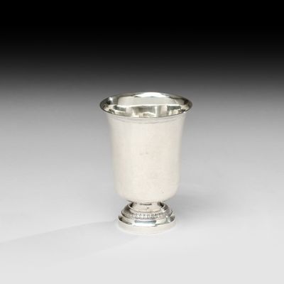 une coupe en argent posée sur un socle, sur une surface blanche