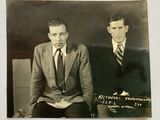 an old photo of two men sitting next to each other