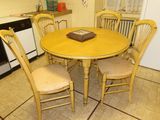 a yellow table and four chairs in a small kitchen