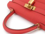 the red leather handbag with gold hardware is on a white surface