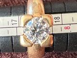une bague en or sertie d'un diamant posée sur une règle