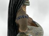 a ceramic vase with a woman sitting on a rock