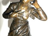 a bronze statue of a woman talking on a cell phone