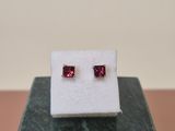 a pair of ruby earrings sitting on top of a marble block