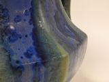 a blue and green vase sitting on a white table