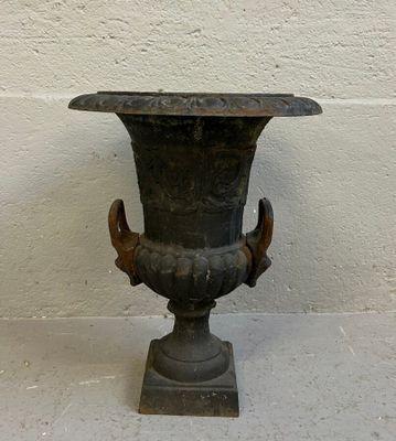 un vase noir posé sur un socle au sol