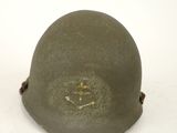 un vieux casque militaire orné d'un smiley, posé sur une surface blanche