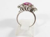 a close up of a ring with a pink stone surrounded by diamonds