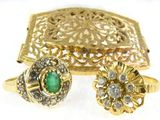 two gold rings and a ring with a green stone in it