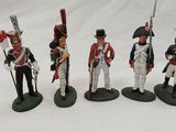 five figurines of soldiers in uniforms and weapons on a white surface