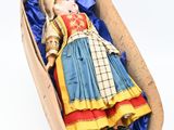 a doll in a wooden box with a blue cloth
