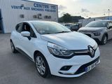 une voiture blanche garée devant un immeuble, à côté d'autres voitures